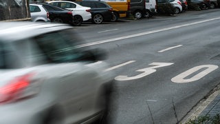 Ein Auto fährt über eine Straße auf der eine große 30 aufgemalt ist.