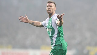 Werder-Verteidiger Mitchell Weiser breitet die Arme aus.