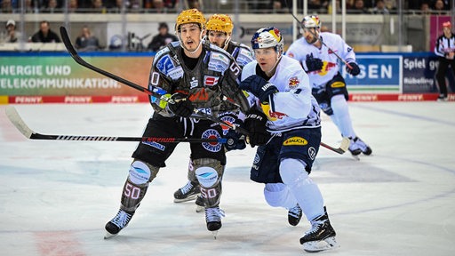 Spieler der Pinguins und des EHC München duellieren sich um den Puck.