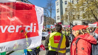 Mehrere Verdi-Mitglieder demonstrieren auf einem öffentlichen Platz. 