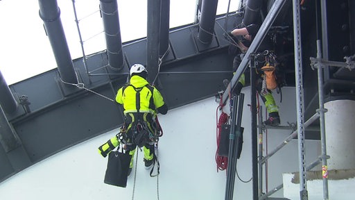 Zwei Industriekletterer während der Arbeit an einer Hallendecke.