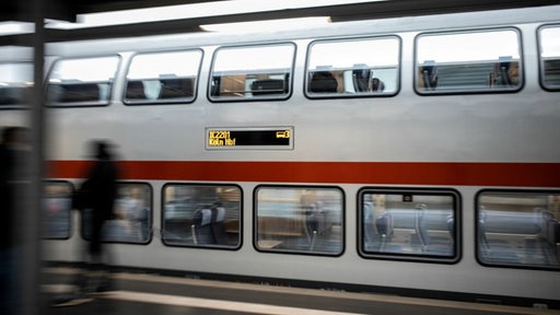 Ein Zug fährt an einem Bahnsteig.