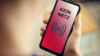 Hand hält ein Handy mit der Aufschrift: Kein Netz. 