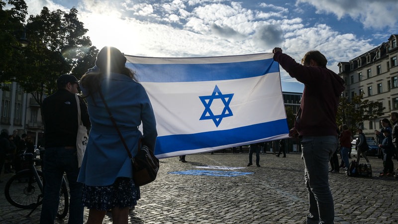 Demonstranten halten eine israelische Fahne hoch. 