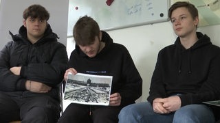 Jugendliche im Interview. Ein Jugendlicher hält ein Foto vom Auschwitzer Konzentrationslager in den Händen.