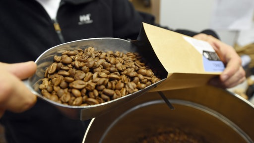 Ein Mann füllt beim Bremer Cross Coffee in der Rösterei Bohnen in eine Verpackung.