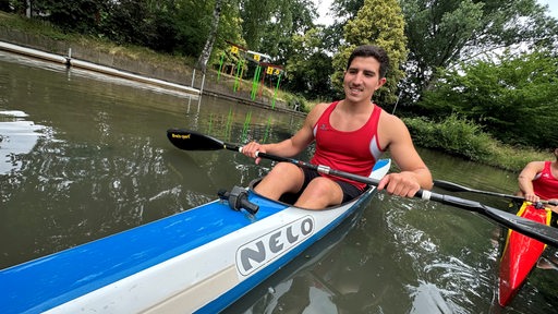 Der iranische Kanut Iliya Nadernejad paddelt lächelnd auf dem Uni-See.