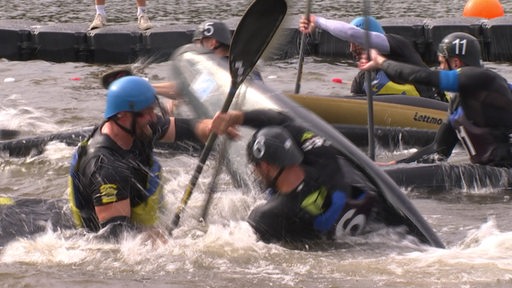 Mehrere Sportler treten mit vollem Einsatz auf dem Werdersee im Kajakpolo an.