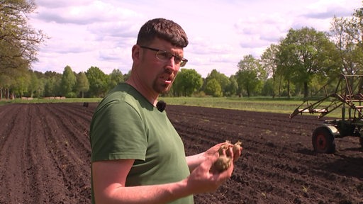 Der Landwirt Frank Lütjen auf seinem Acker mit Kartoffeln in der Hand.