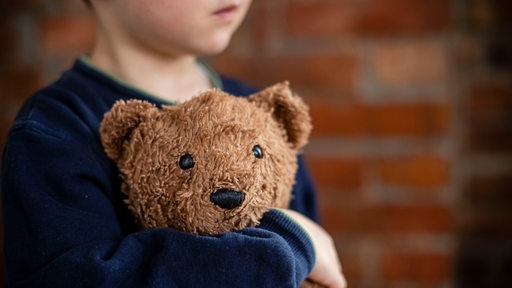 Ein kleiner Junge kuschelt mit seinem Kuscheltier.