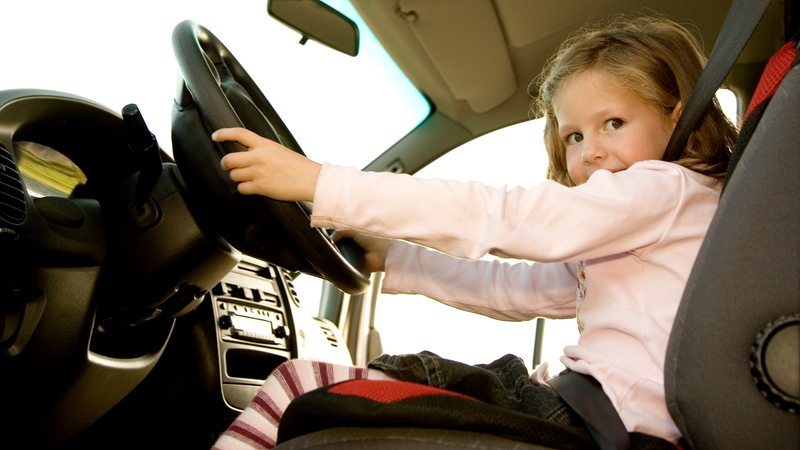 Ein Mädchen sitzt hinter dem Steuer eines Autos