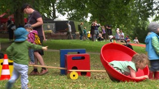 Kinder spielen auf der Wiese in verschiednen Spielsachen.