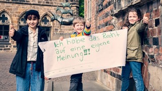 Ein Kind hält ein Schild mit dem Titel: "Ich habe das Recht auf eine eigene Meinung!"