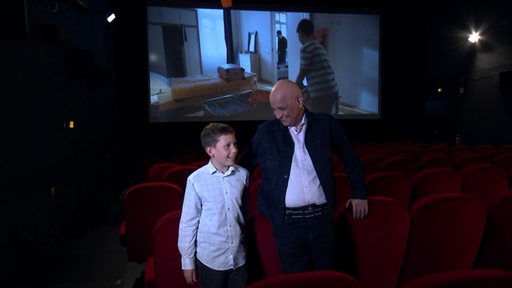 Der Regisseur des Films "Sieben Tage" Ali Samadi steht neben dem Kinderschauspieler Sam Vafa in einem Kinosaal