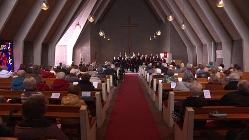 Eine Kirche mit besetzten Bänken.