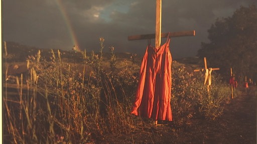 Ein Kleid an einem Holzkreuz.