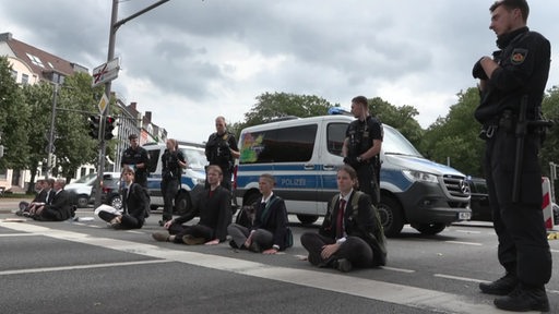 Zu sehen sind Klimaaktivisten, welche sich auf die Straße geklebt haben.