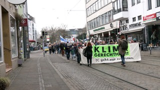 Menschen laufen mit Transparenten durchs Bremer Viertel.