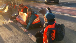 Klimaaktivisten haben sich auf der Straße vor dem Kühne&Nagel-Gebäude festgeklebt.