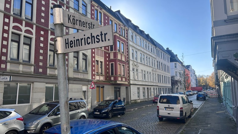 Blick in eine Straße mit Mehrfamilienhäusern. Auf den beiden Straßenschildern stehen "Körnerstraße" und "Heinrichstraße".