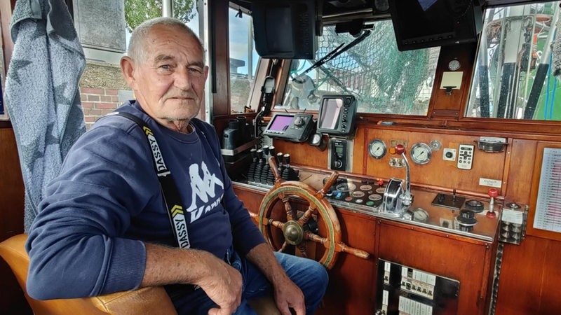 Rentner Hans-Joachim Reim sitzt am Steuer seines Fischkutters und hat einen grimmigen Blick. 