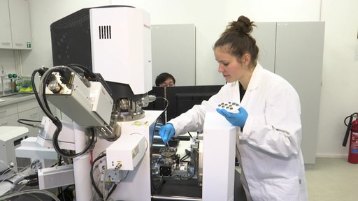 Eine Wissenschaftlerin in weißem Kittel arbeitet im neuen Gerätezentrum an der Hochschule im Labor.