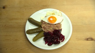 Eine Portion Labskaus mit Rote Beete Salat, sauren Gurken und einem Spiegelei