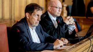 Der angeklagte Pastor Olaf Latzel sitzt vor Prozessbeginn mit seinem Anwalt Sascha Böttner in einem Gerichtssaal im Landgericht Bremen.