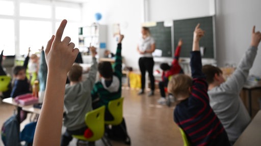 Schüler einer Grundschule recken ihre Finger nach oben.