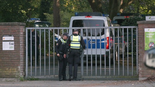 Polizeifahrzeuge fahren durch die Einfahrt des Friedhof Walle