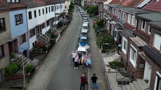 Menschen stehen auf einer Straße in Walle und winken.