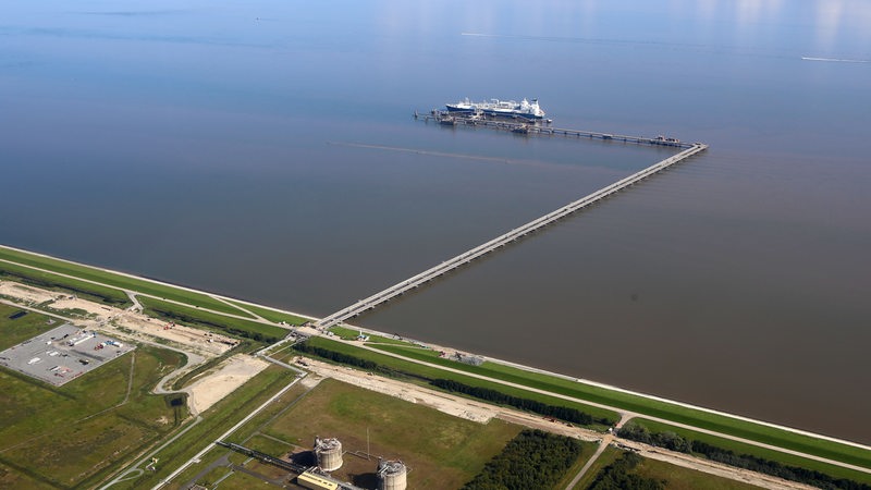 Ein Schiff liegt vor einer Küstenlinie. Es handelt sich um das LNG-Speicherschiff "Höegh Esperanza".