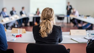 Rückenansicht einer Frau in Businesskleidung in einer Besprechung.