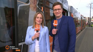 Lea Reinhard und Felix Krömer vor der buten un binnen Straßenbahn,