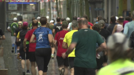 Teilnehmer eines Marathons laufen eine Straße entlang