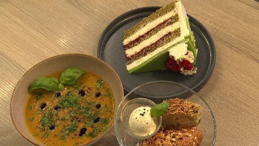  Eine Himbeer-Vanille- Matcha-Frühlingstorte mit unterschiedlichen Beilagen serviert.