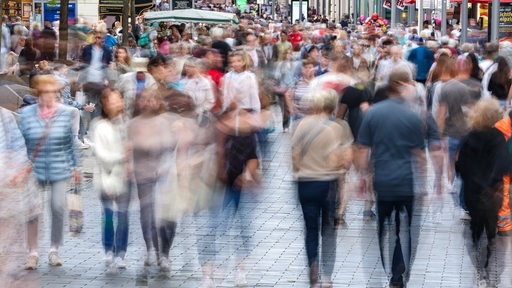 Viele Menschen laufen durch eine Innenstadt.