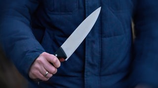Ein Mensch hält ein Messer fest in der Hand.