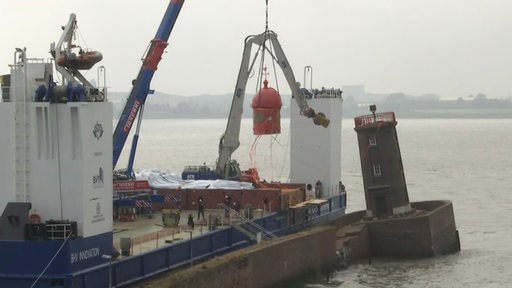 Die Kuppel des Molenturms in Bremerhaven schwebt an einem Kran neben dem Turm.