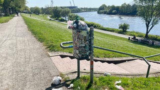 Ein voller Mülleimer am Osterdeich, vor dem Müll auf dem Boden liegt