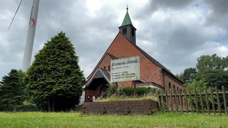 Vor einer Kirche steht ein Schild.