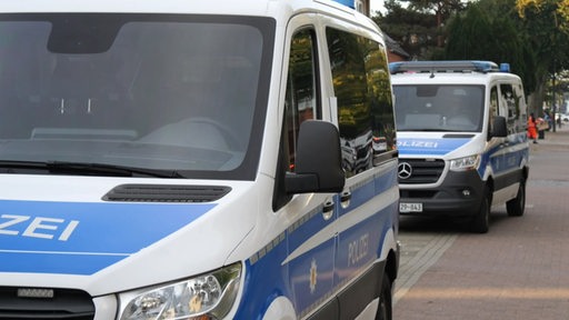 Zwei Polizeiwagen parken vor Wohungen und Häsuern. 