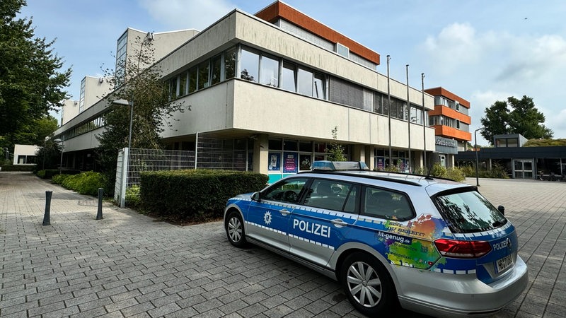 Ein Polizeiauto steht vor einem Schulgebäude