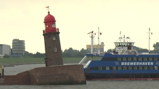 Hinter dem schiefen Molenturm von Bremerhaven fährt eine personenfähre vorbei.