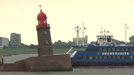 Hinter dem schiefen Molenturm von Bremerhaven fährt eine personenfähre vorbei.