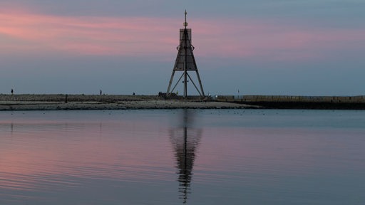 Ein Seezeichen spiegelt sich bei Sonnenuntergang im Wasser.