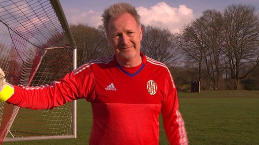 Der Webseitendesigner Norman Böttger steht in seinem Fußballtrikot ans Tor gelehnt.