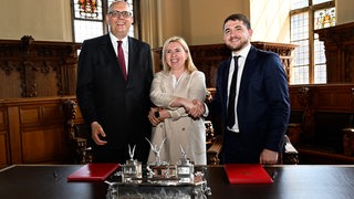 Drei Politiker stehen im Bremer Rathaus.