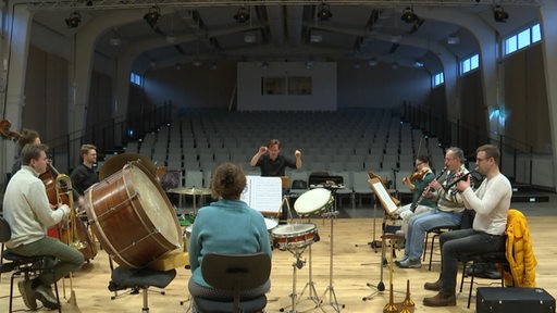 Mehrere Musiker und Musikerinnen proben im Orchester.