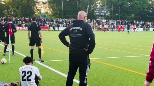 Zu sehen ist der Trainer des OSC Brmerhaven, welcher am Spielfeldrand steht.